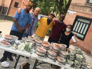 Stan Morse ’85 stands with a group in front of a table of food in takeout containers.