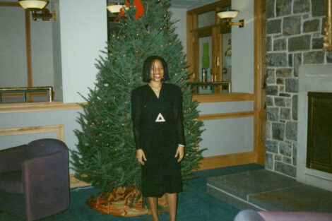 A woman stands in front of a Christmas tree.