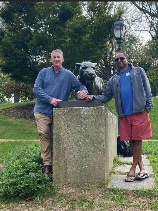 two men standing on each side of a leopard statue